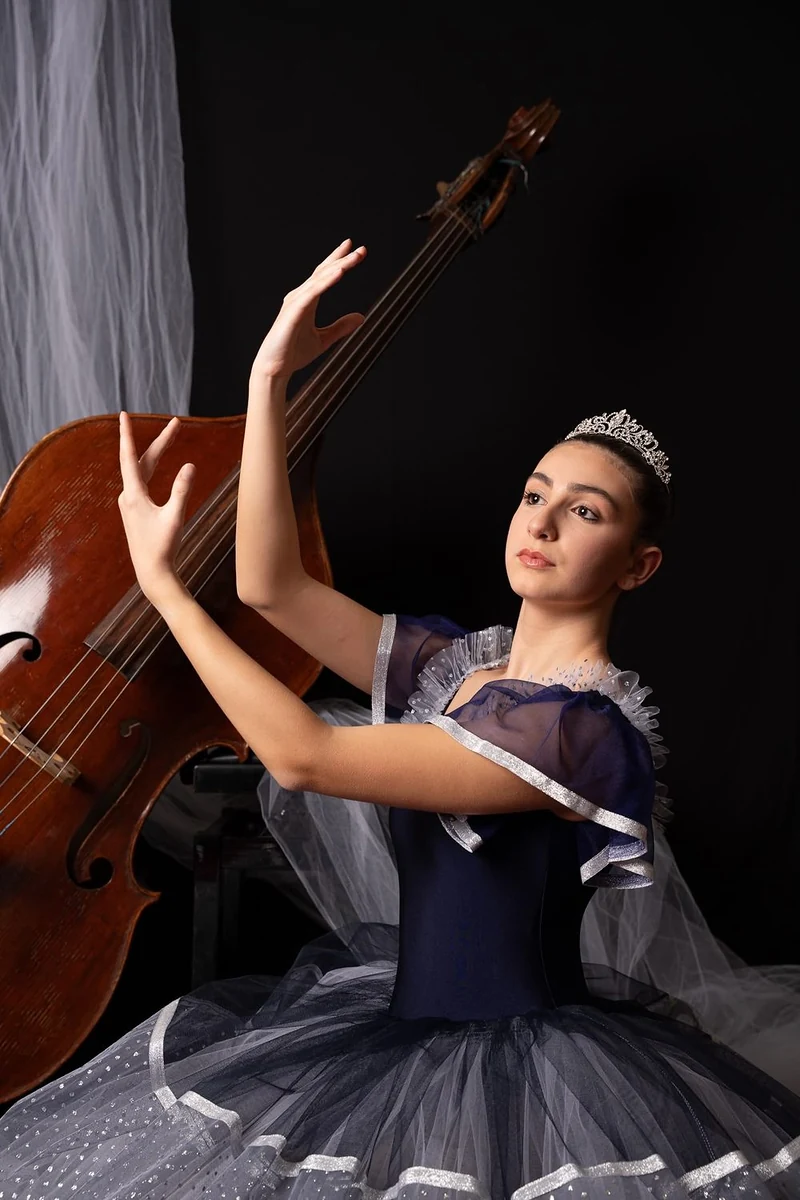 Ballerina con tutù blu e diadema in posa davanti a un contrabbasso