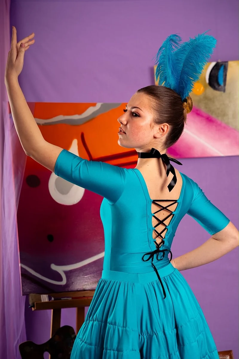Ballerina di spalle in abito turchese con corsetto allacciato e piume blu