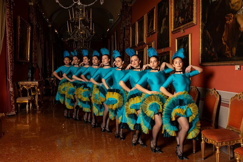 Fila di ballerine di can-can in costume turchese in una galleria di palazzo