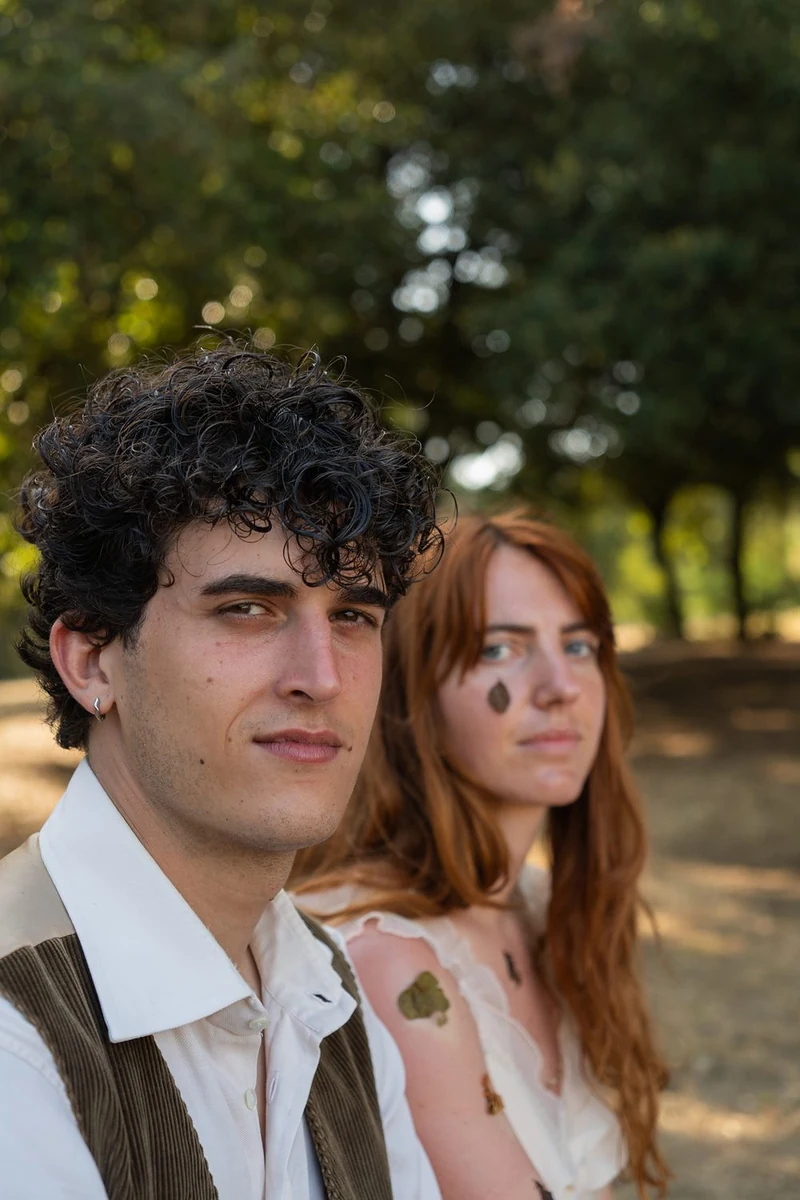 Ragazzo riccio e ragazza dai capelli rossi seduti vicini nel bosco