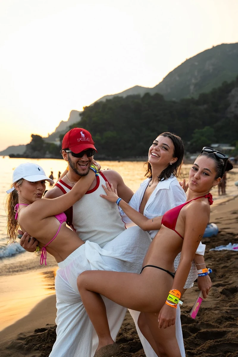 Amici che posano ridendo sulla spiaggia al tramonto durante una vacanza di gruppo