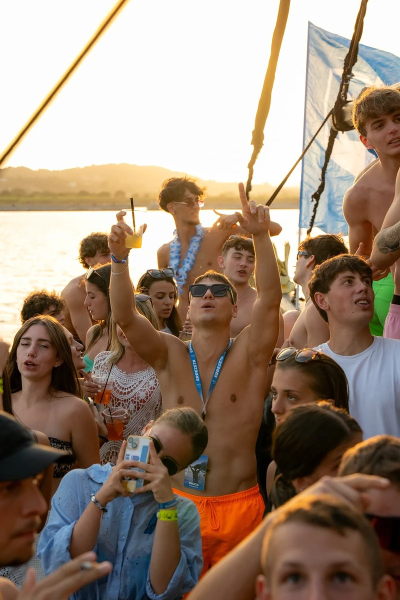 Gruppo di ragazzi che festeggia su una barca al tramonto