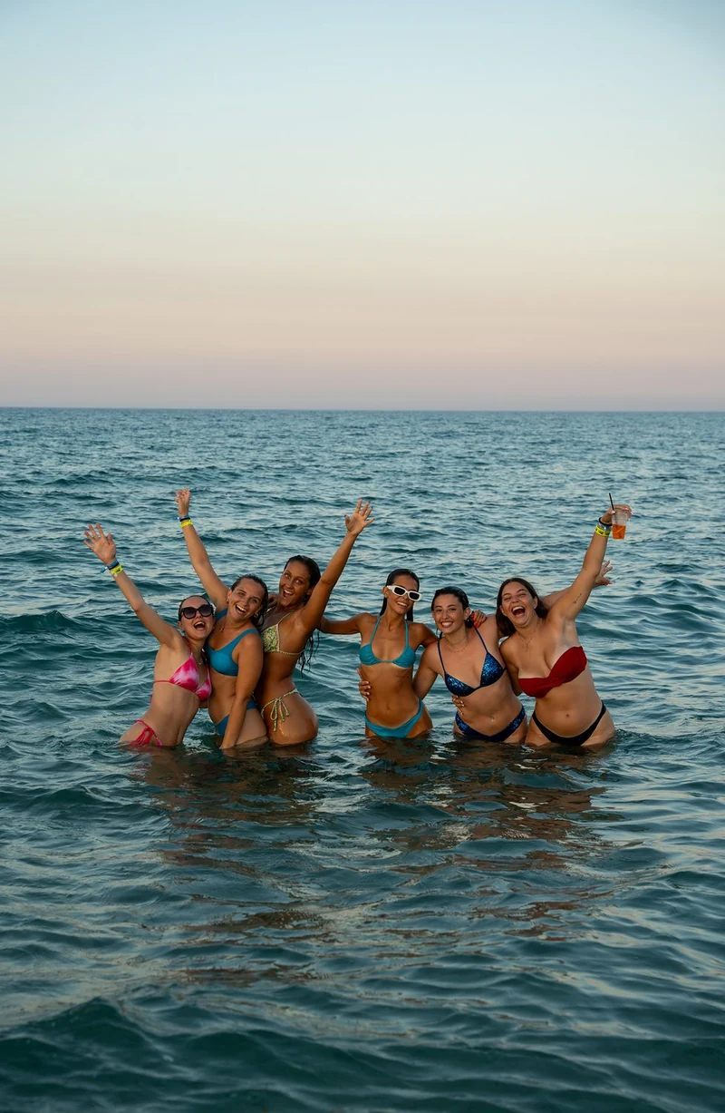 Ragazze in costume che salutano dal mare al tramonto