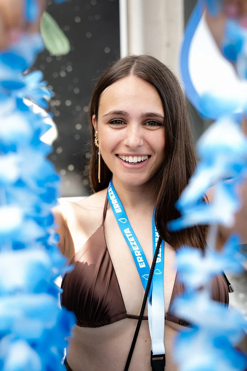 Ragazza sorridente con il pass al collo tra le decorazioni blu di una festa