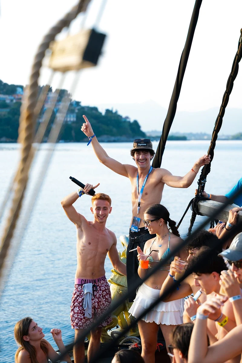 Ragazzi che ballano a bordo di una barca a vela con il mare sullo sfondo