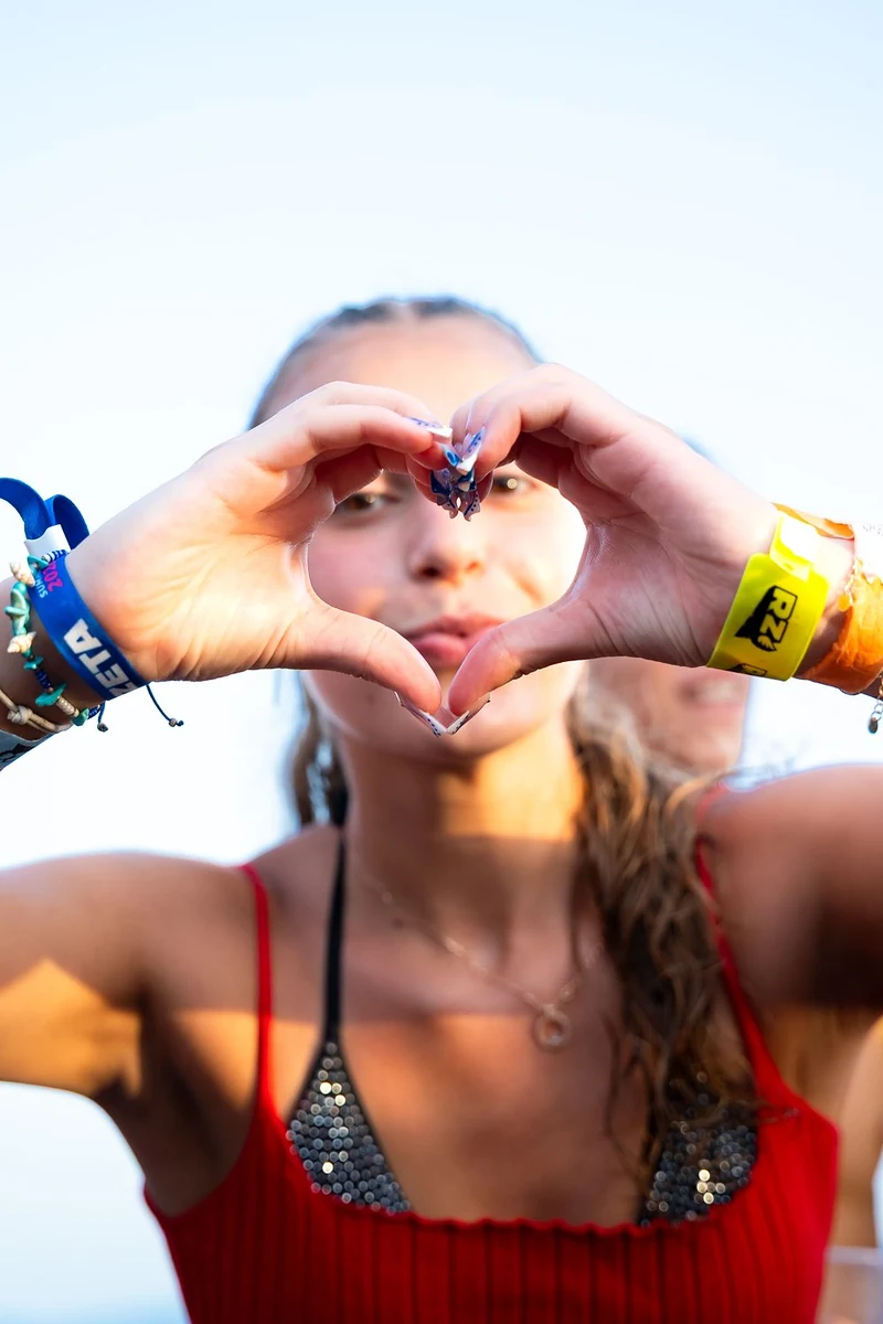 Ragazza che fa un cuore con le mani durante una festa al mare