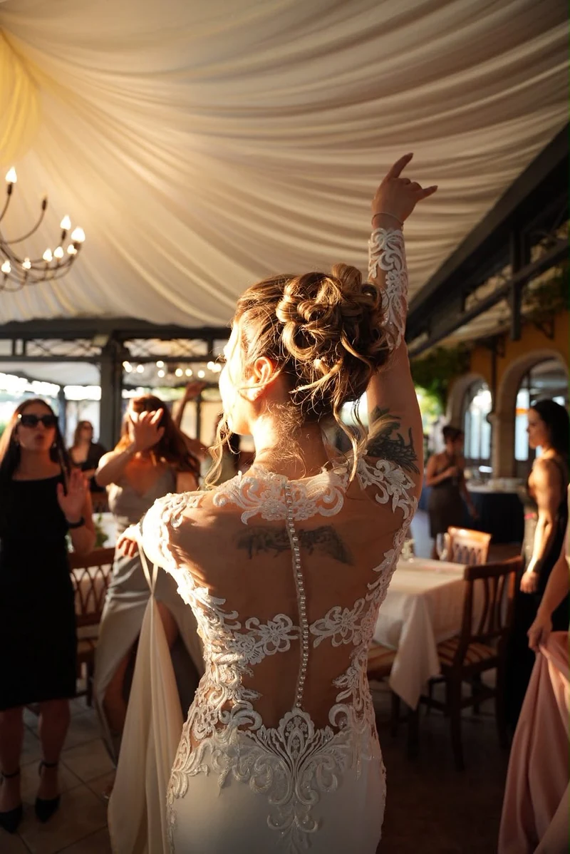 Sposa di spalle con l'abito di pizzo trasparente che balla sotto il tendone del ricevimento