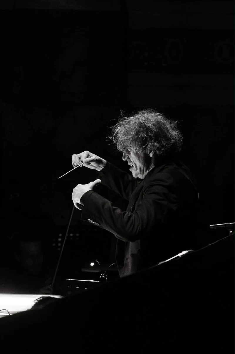 Direttore d'orchestra con la bacchetta in penombra, in bianco e nero