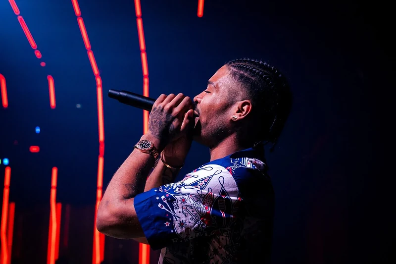 Rapper che canta al microfono sul palco, tra luci rosse e blu