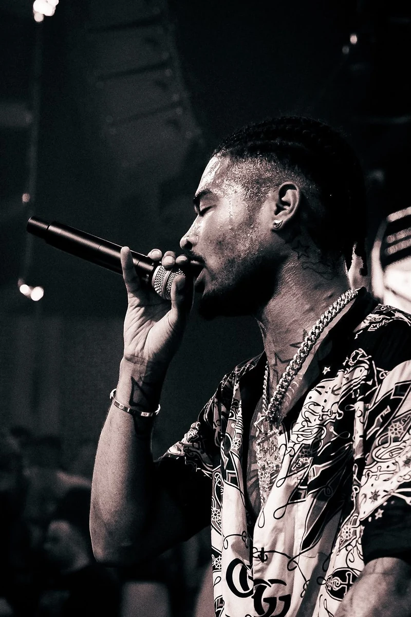 Rapper con la catena al collo che canta al microfono, in bianco e nero