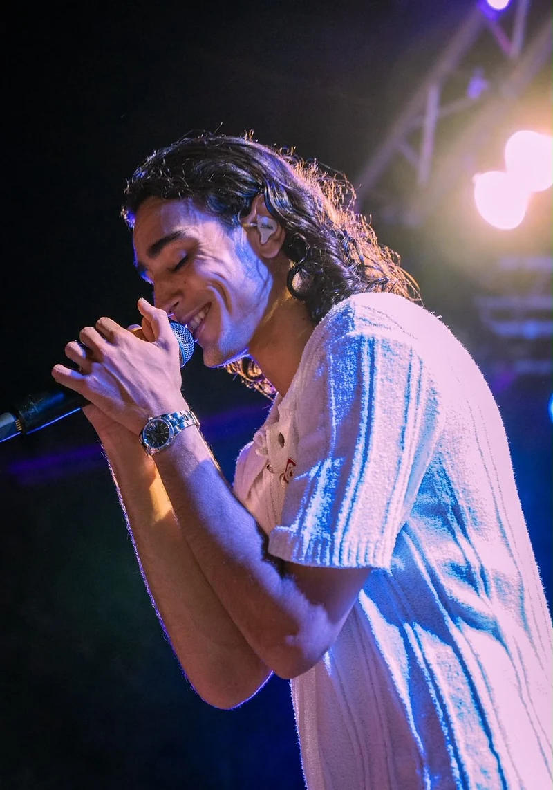 Cantante che canta a occhi chiusi con il microfono tra le mani, luce viola