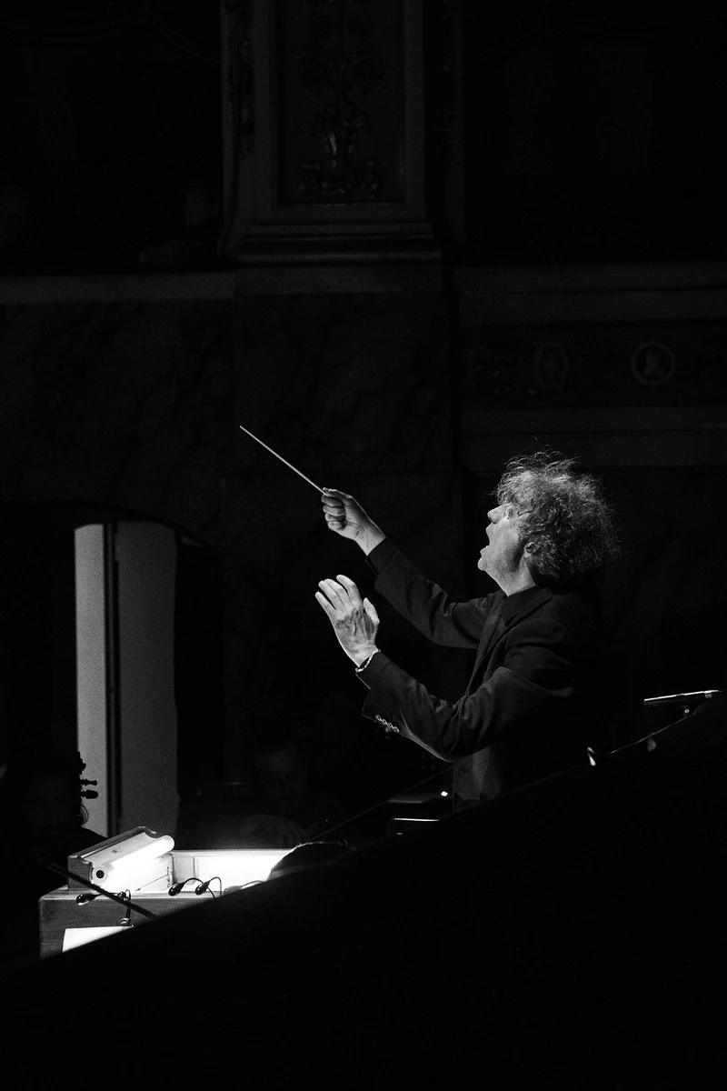 Direttore d'orchestra con le braccia alzate in un teatro, in bianco e nero