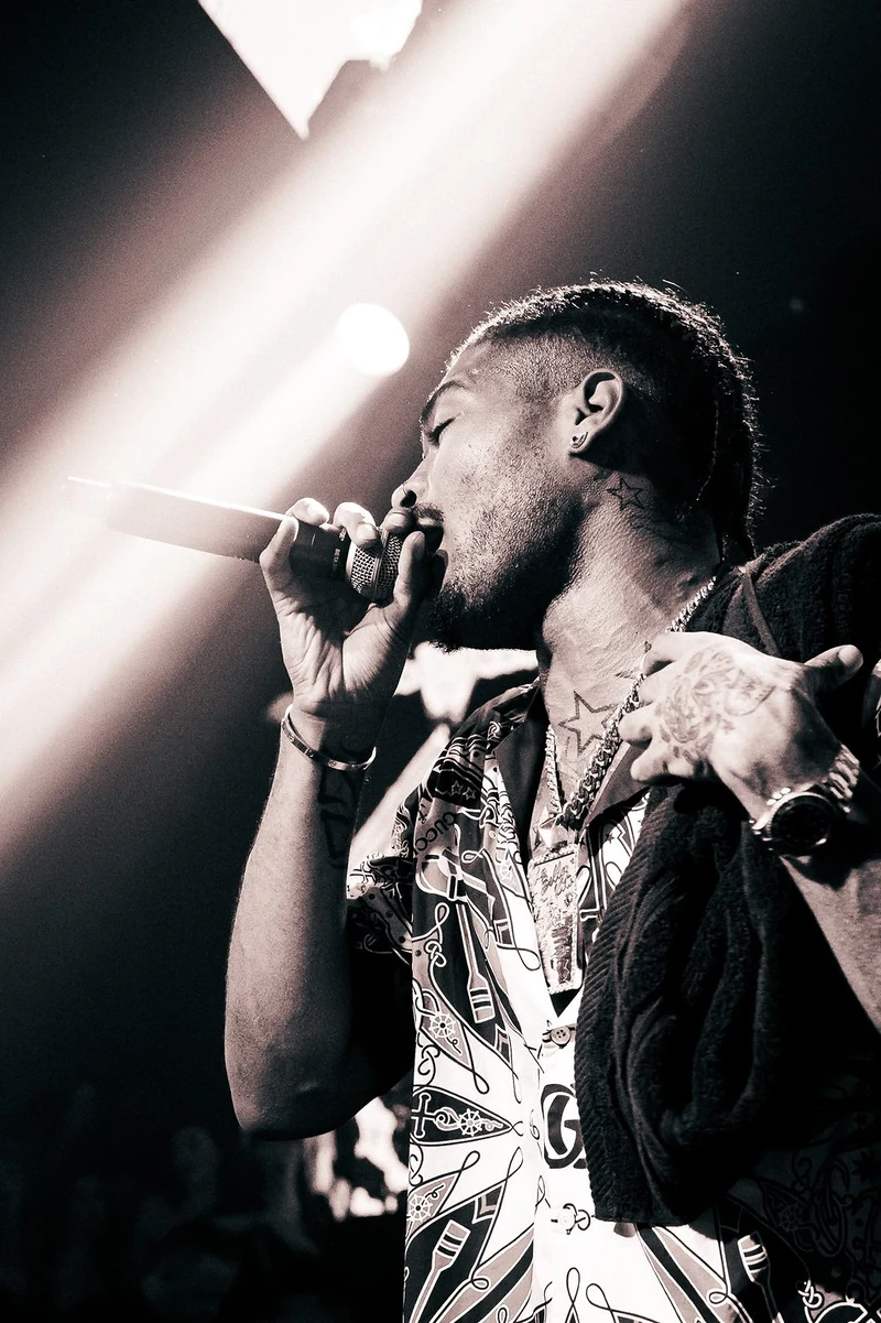 Rapper al microfono in controluce con un fascio di luce bianca