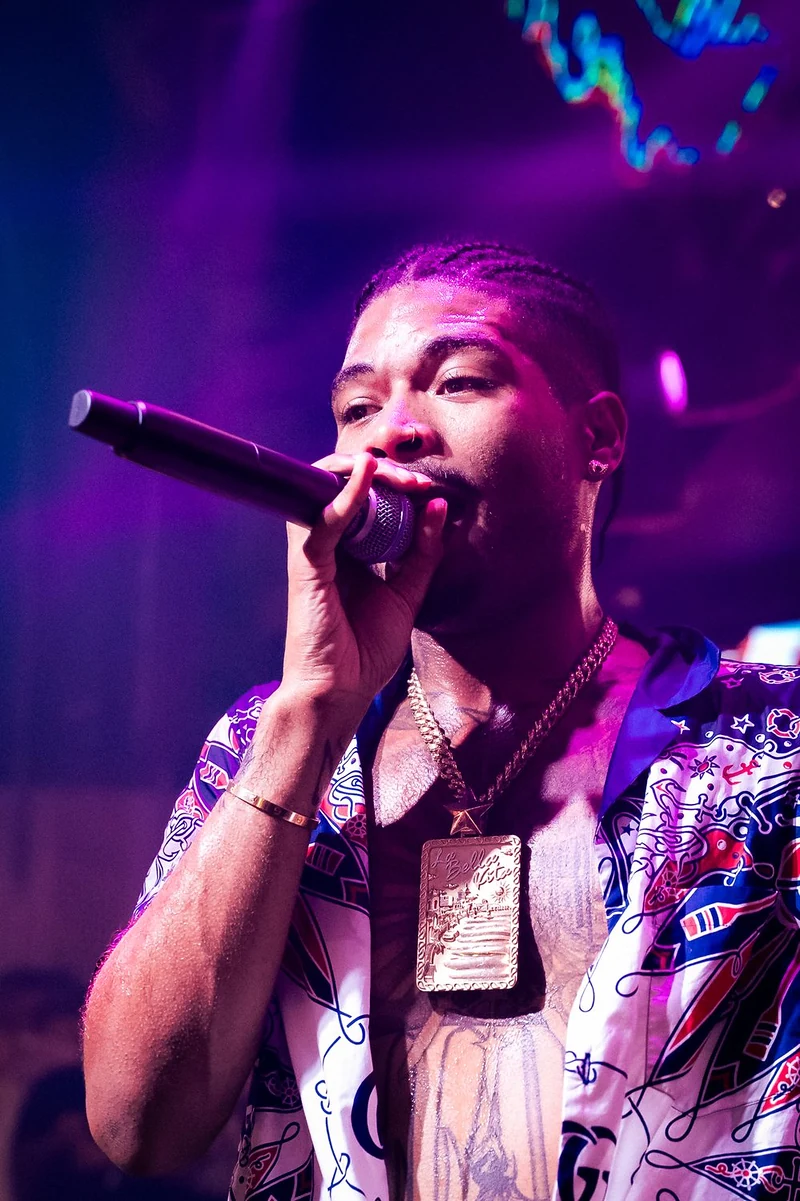 Rapper che canta al microfono sotto le luci viola del palco