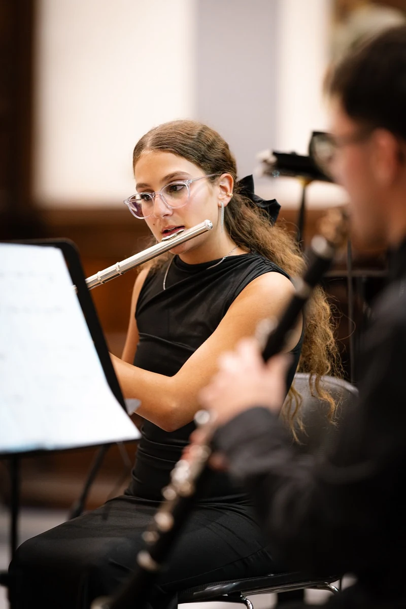 Flautista dietro un clarinetto in primo piano, durante il concerto