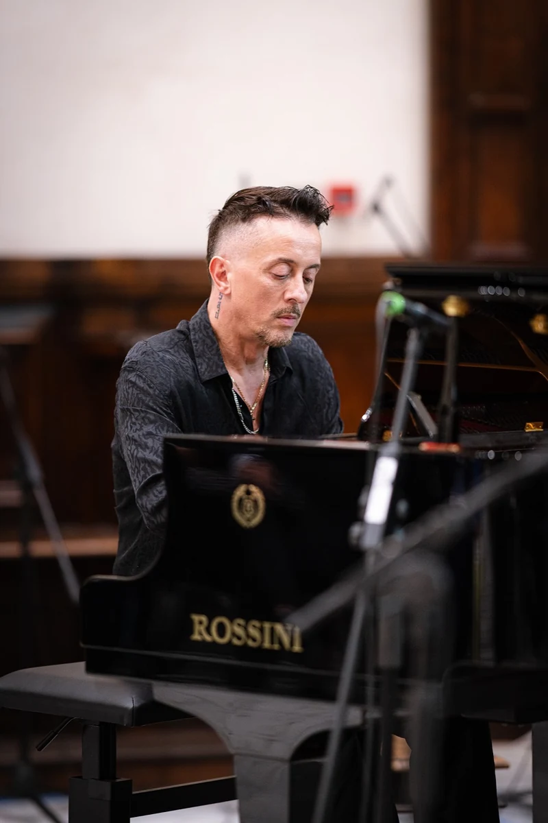 Pianista al pianoforte a coda in una sala con pareti in legno