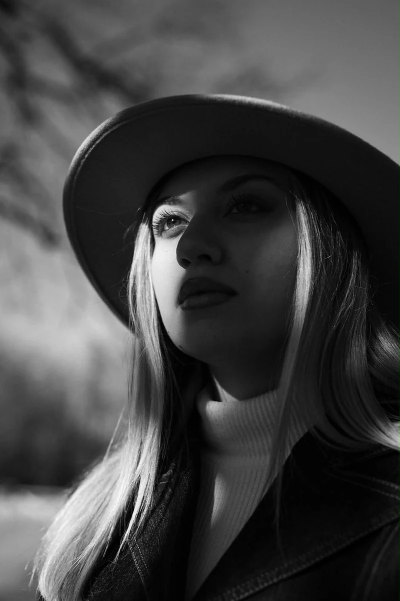 Ritratto in bianco e nero di una donna con il cappello, luce laterale morbida