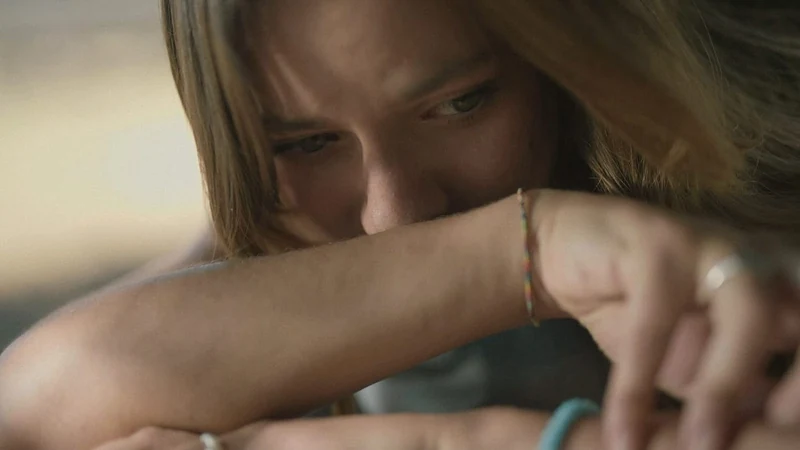 Ragazza con lo sguardo basso e la testa appoggiata sul braccio