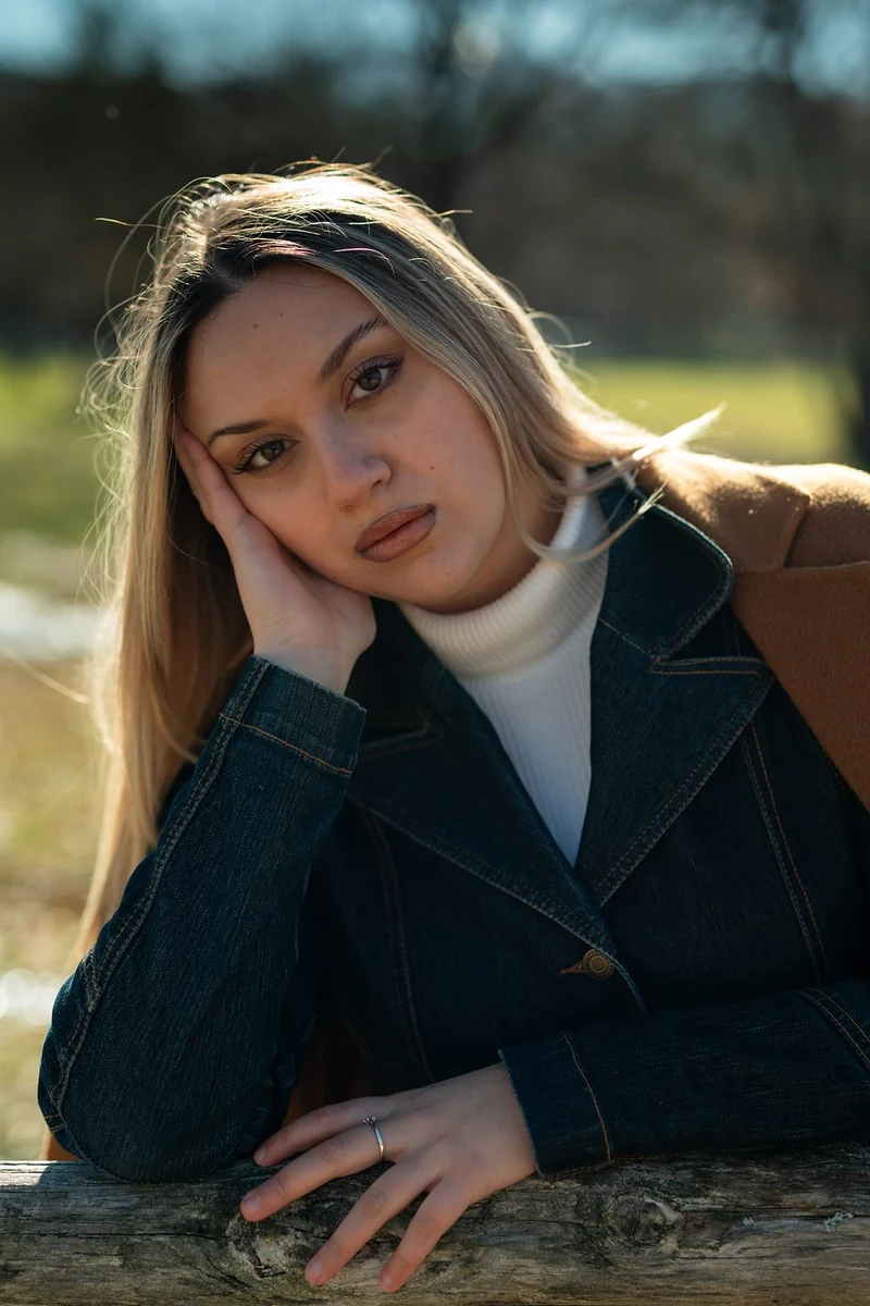 Ragazza bionda in posa con la mano tra i capelli, in luce naturale